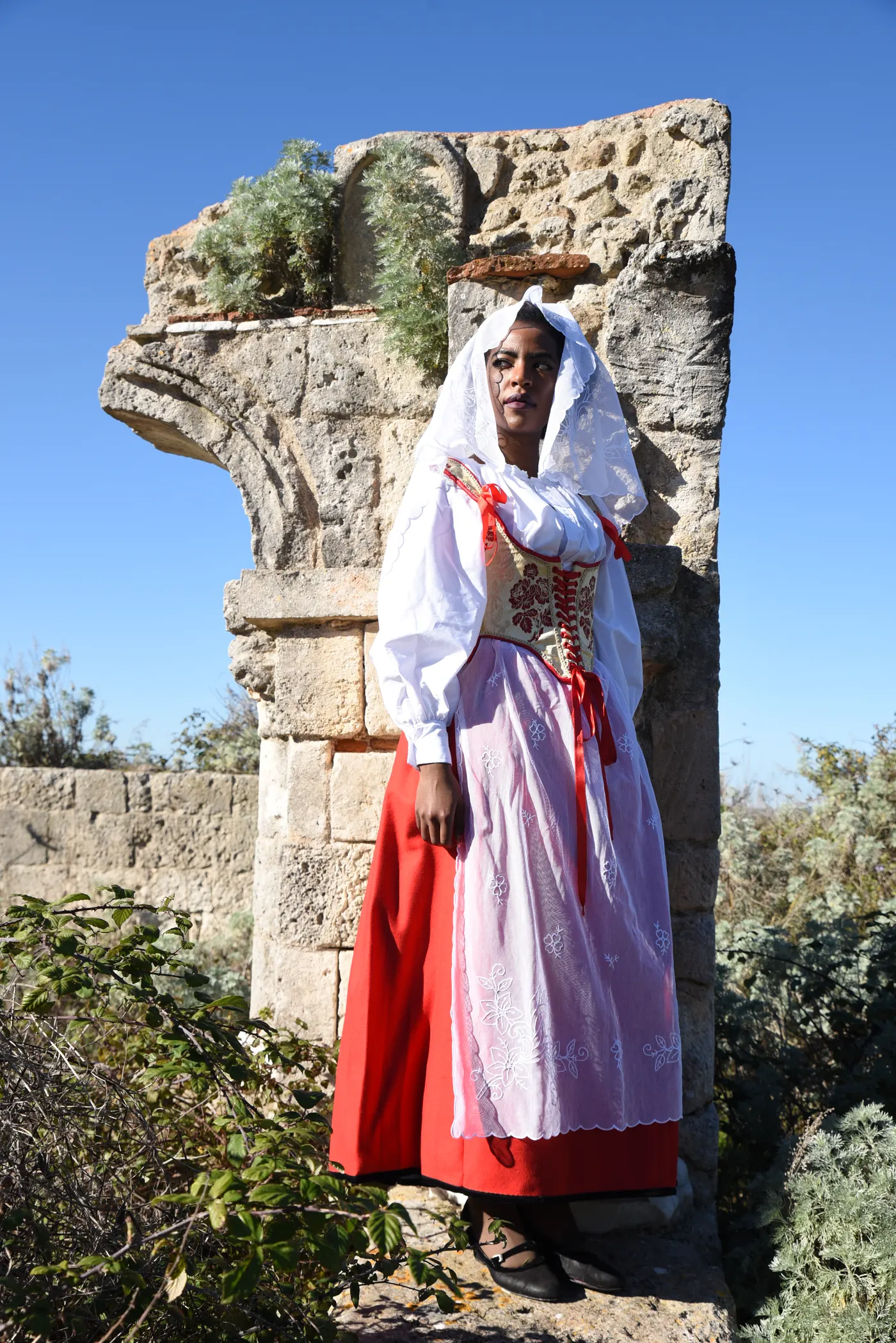 Donna in costume tradizionale sardo in piedi su una colonna antica