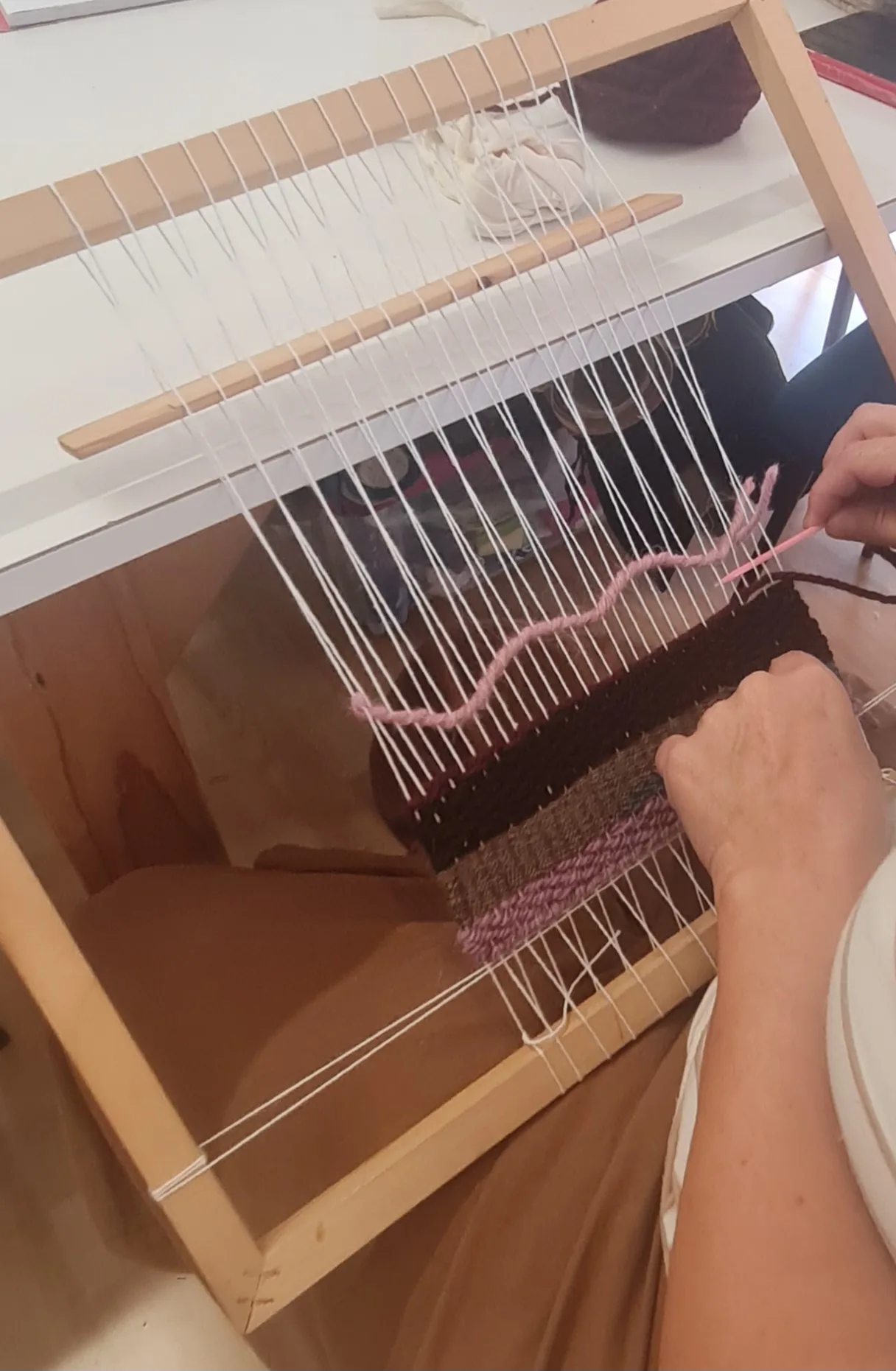 Mani al lavoro su un telaio durante il corso di tessitura